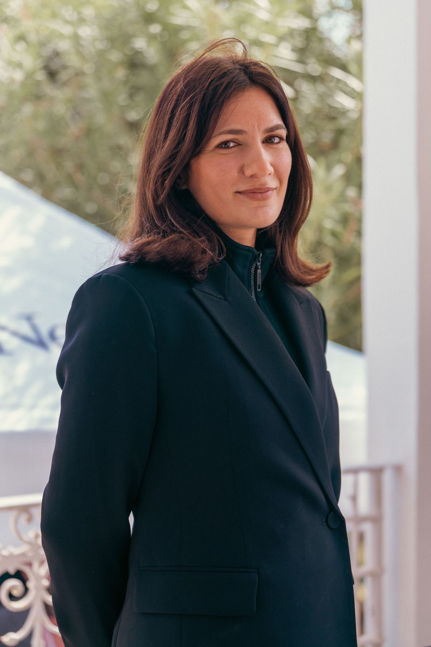 Woman in black coat standing against white background.