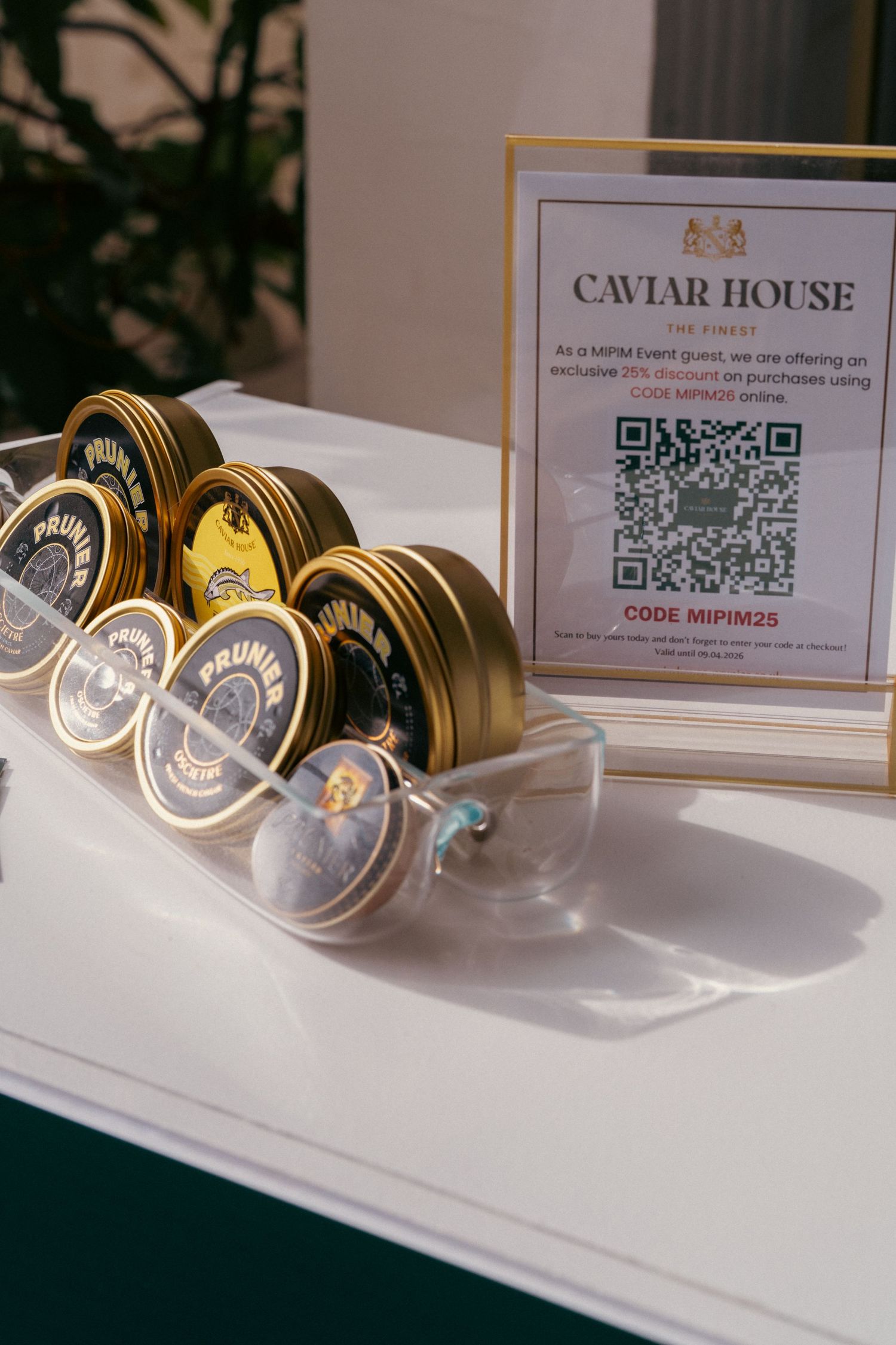 Caviar tins displayed on white surface with QR code signage.