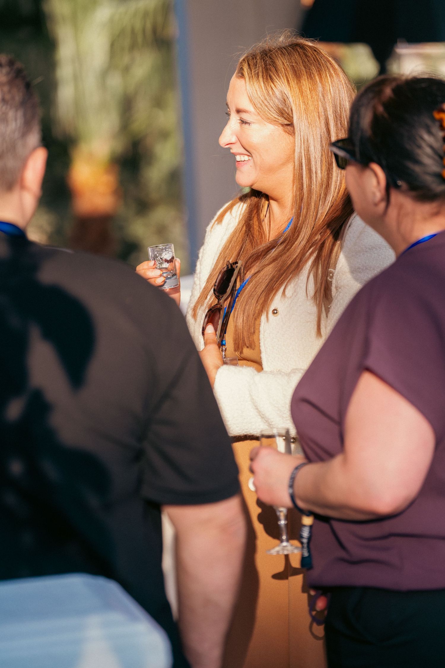 People enjoying drinks and conversation during sunset at outdoor gathering.