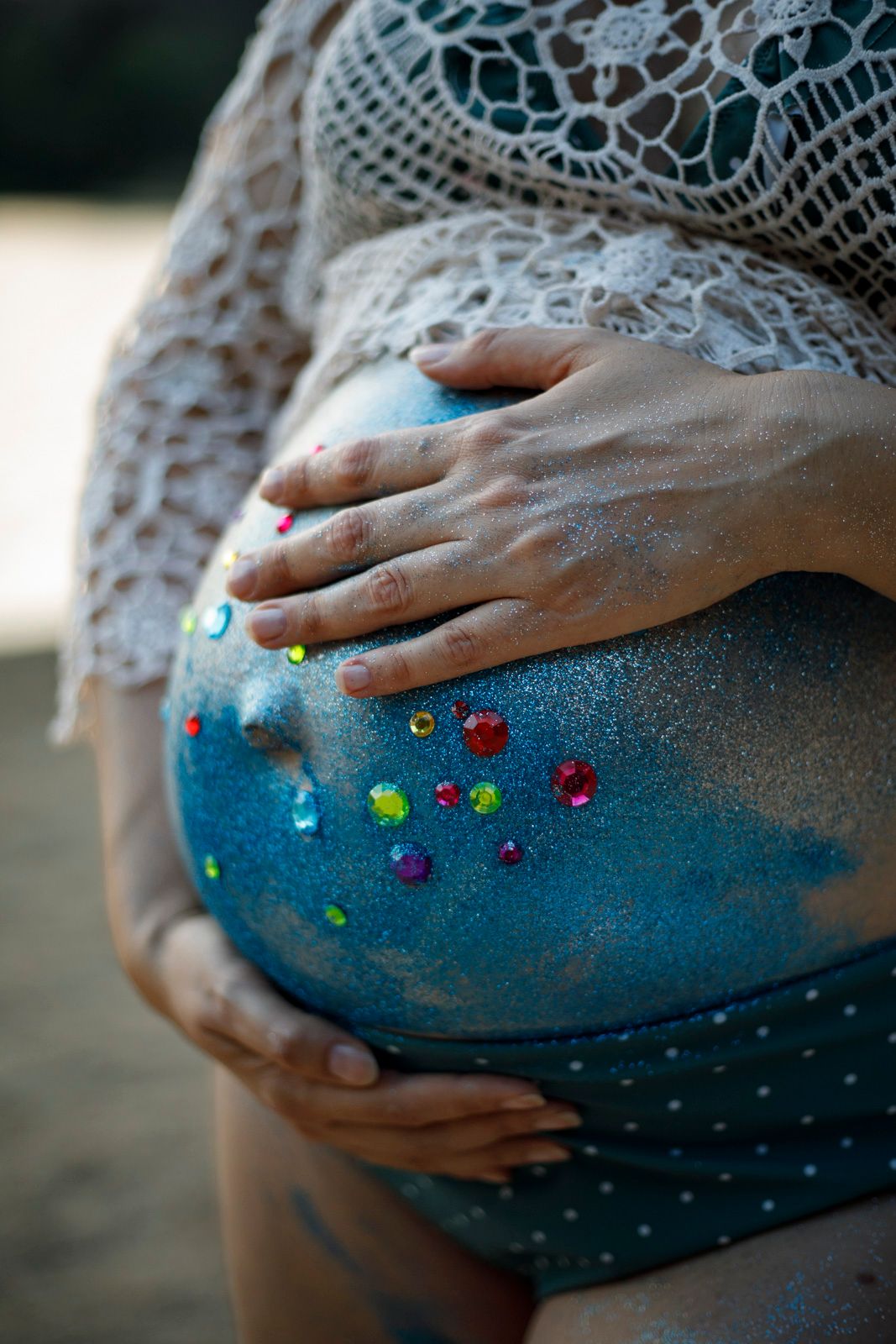 Gros plan sur un belly painting coloré et pailleté sur le ventre d'une femme enceinte