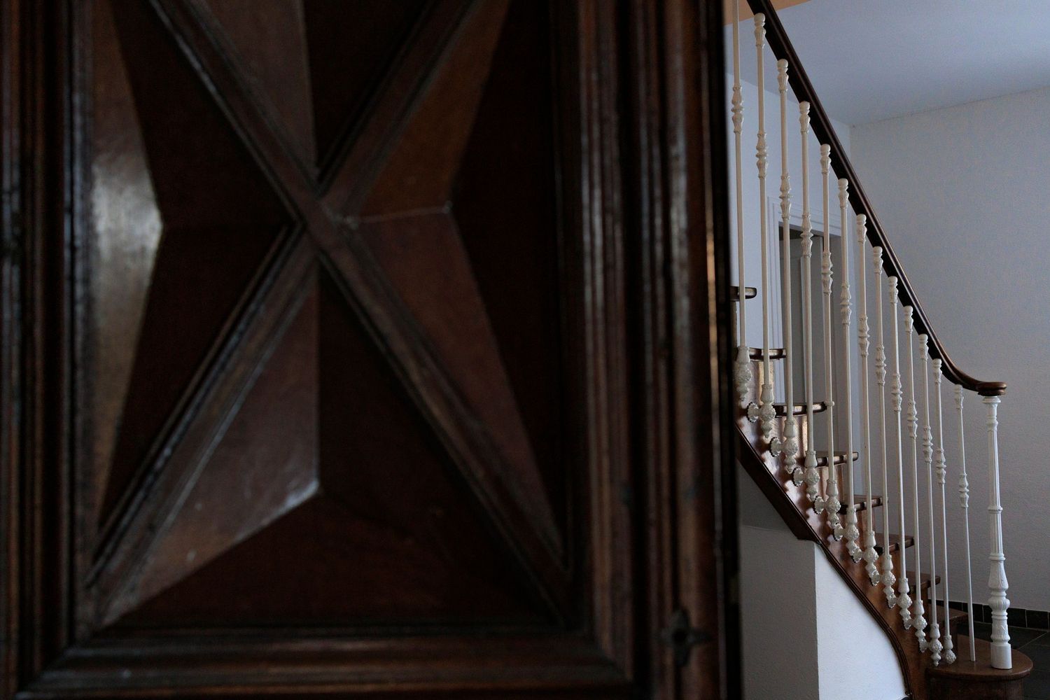 Plan rapproché sur les menuiseries artisanales d'une porte ancienne ouvrant sur un escalier dans un gite de charme près de Mazamet.
