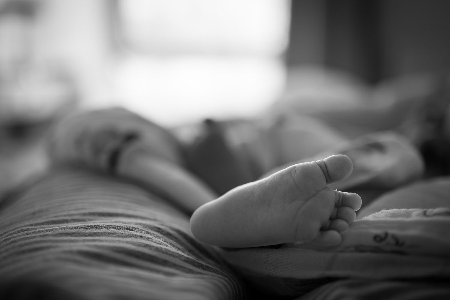 Photo en noir et blanc des petits pieds d'un bébé.