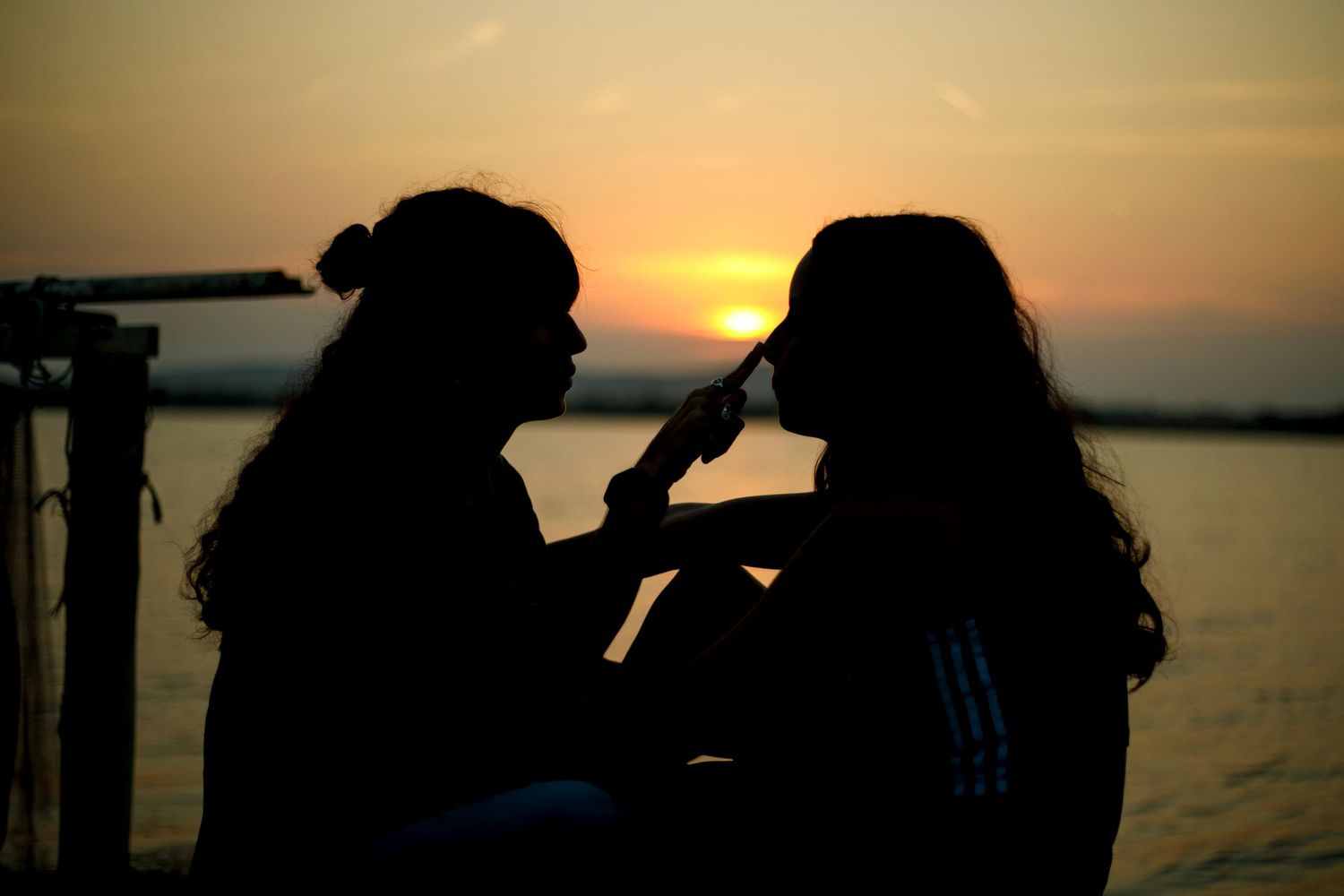 Photo d'un couple de femmes en silhouettes devant le coucher du soleil