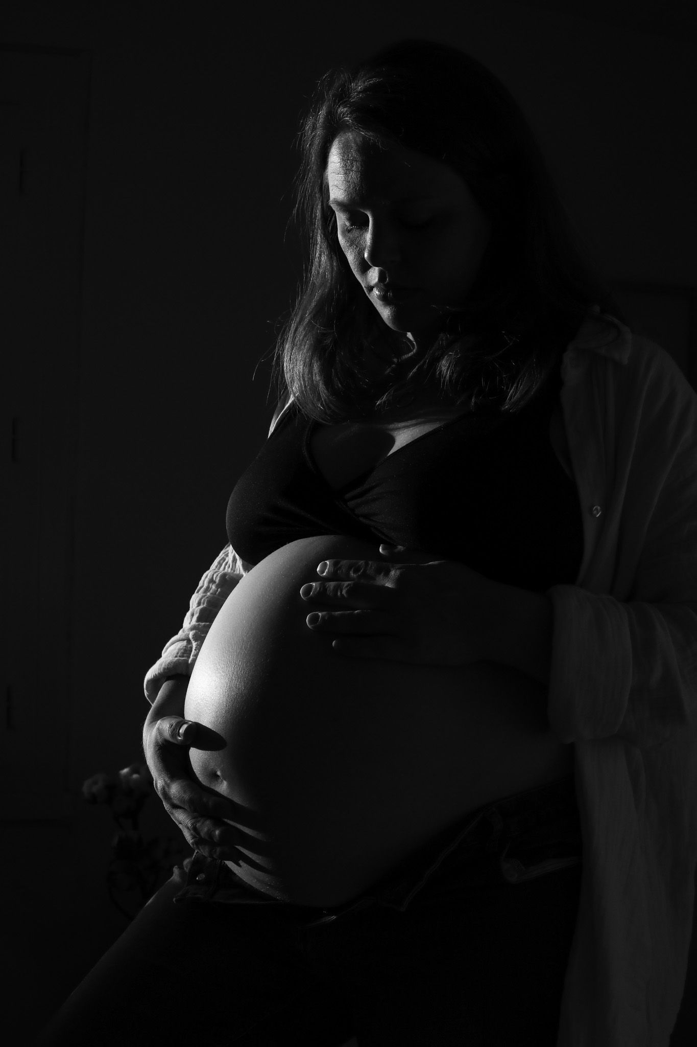 Photographie noir et blanc d'une femme enceinte regardant tendrement son ventre rond