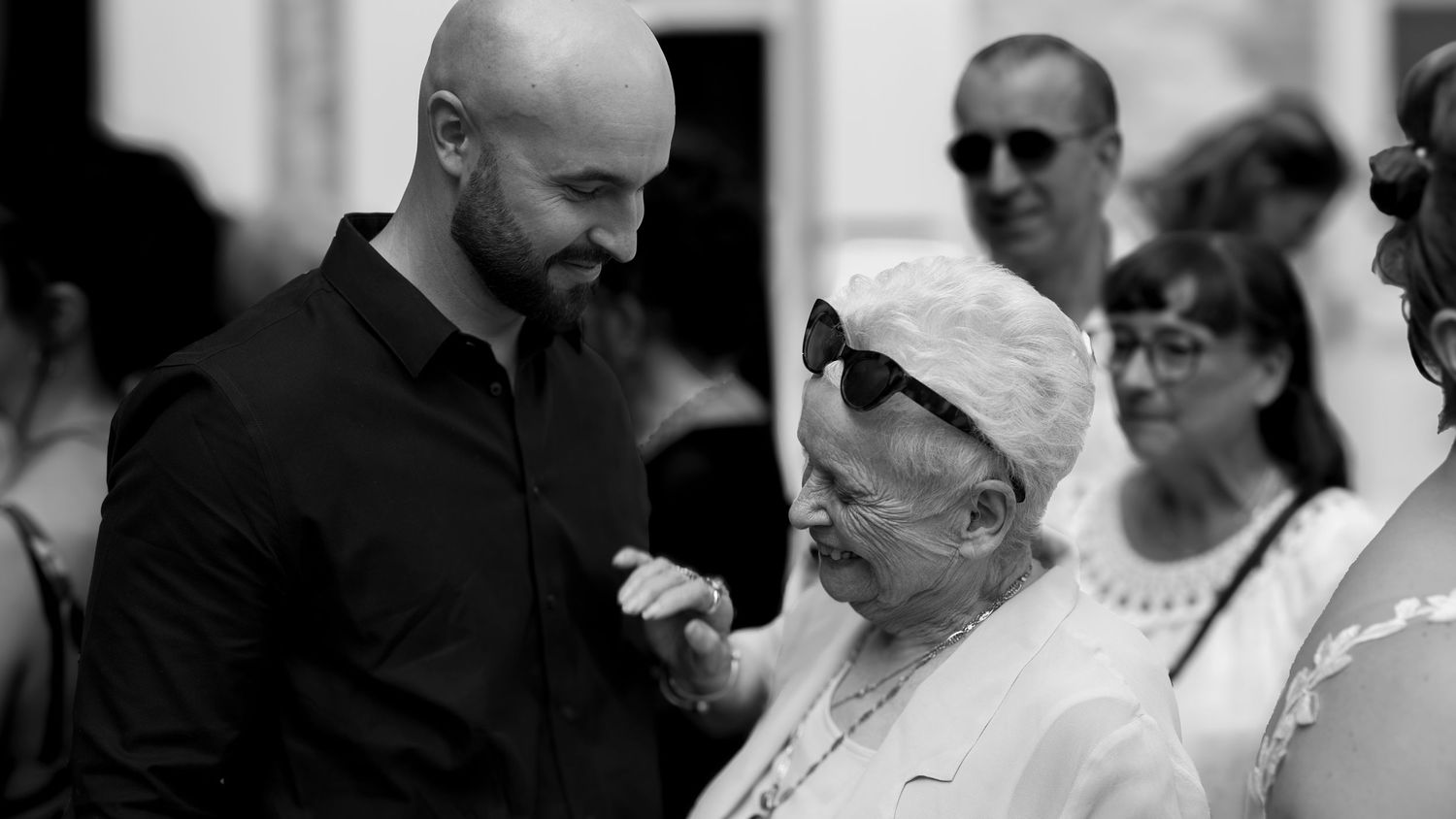 Photographie noir et blanc lors d'un reportage de mariage. Une grand-mère heureuse de retrouver son petit-fils