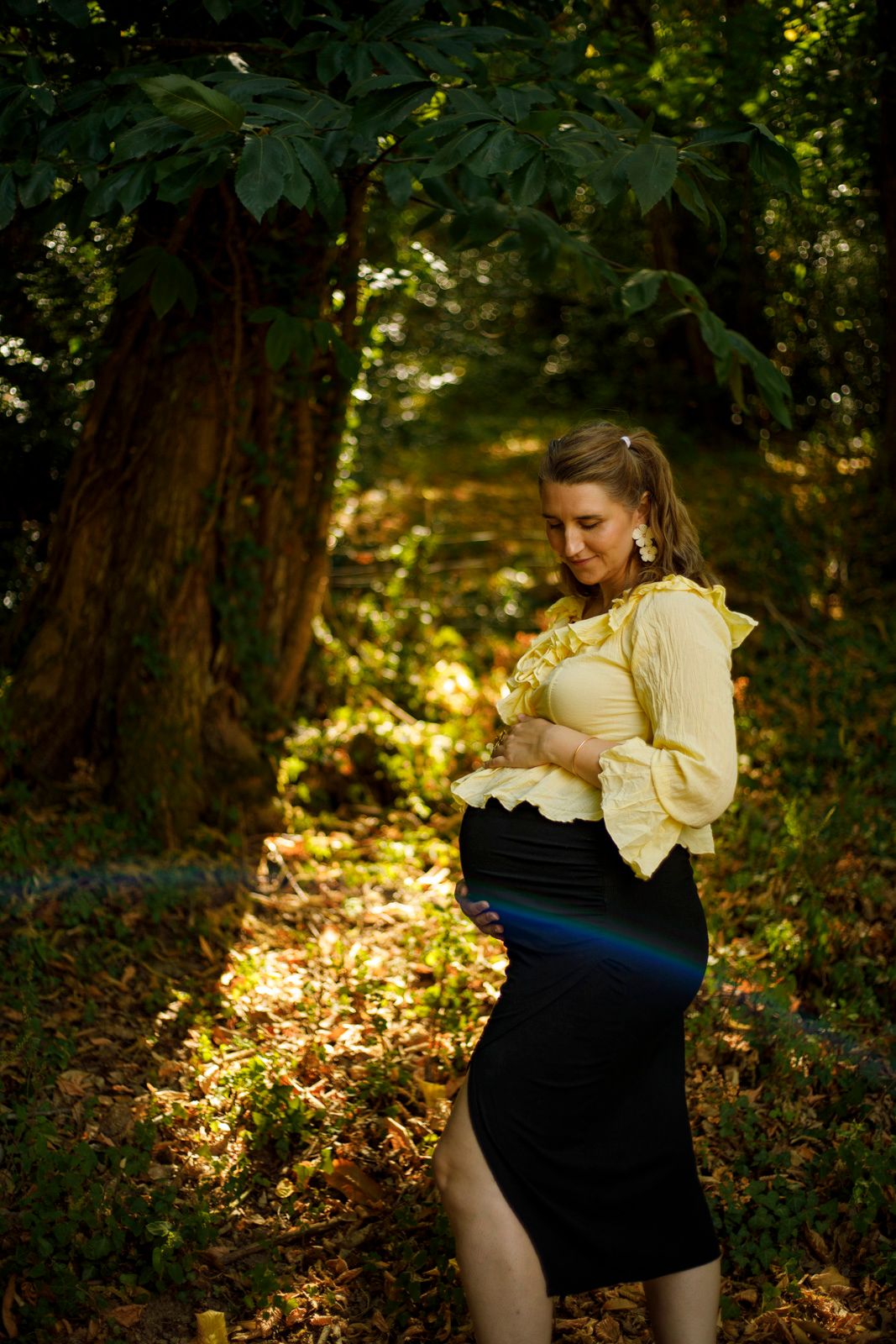 Shooting grossesse en lumière naturelle au cœur d'une forêt lumineuse.