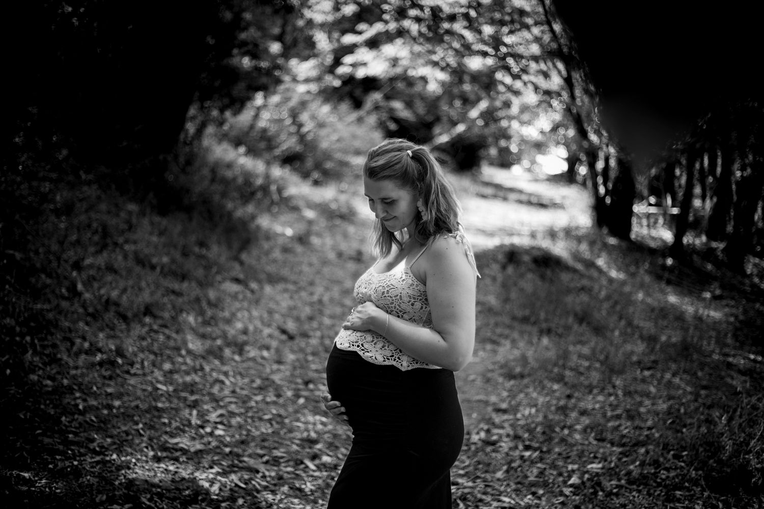 Photographie noir et blanc d'une femme enceinte dans la forêt.