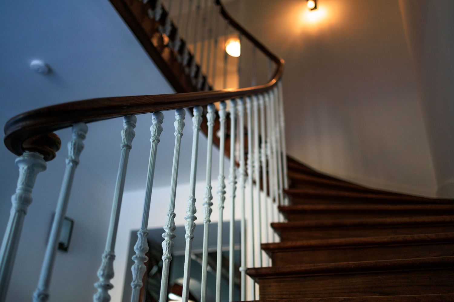 Un magnifique escalier en colimaçon en bois avec une balustrade peinte en blanc remonte vers l'étage des chambres d'un domaine du Tarn.