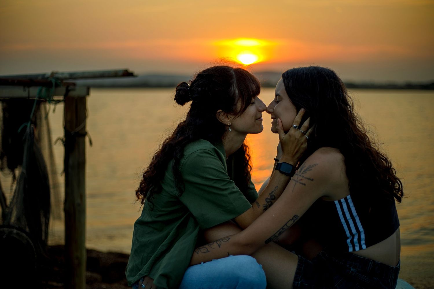 Photo d'un couple de femmes assisent devant le coucher du soleil, les visages très proches