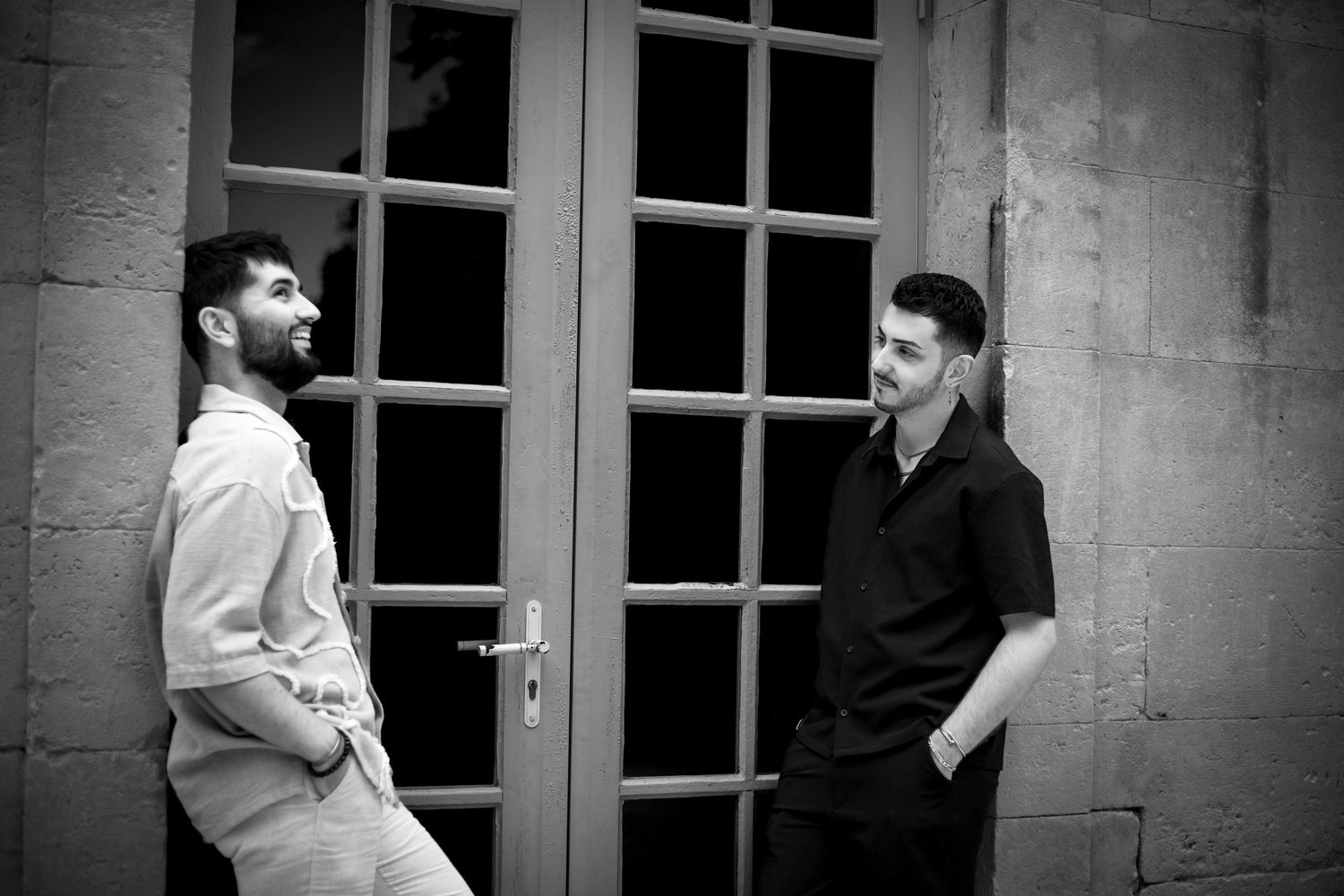 Photo de deux hommes adossés dans l'encadrement d'une porte fenêtre