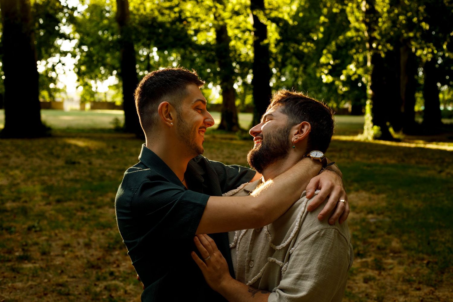 Photo couple gay qui sourient et se regardent tendrement enlacés dans les bras l'un de l'autre