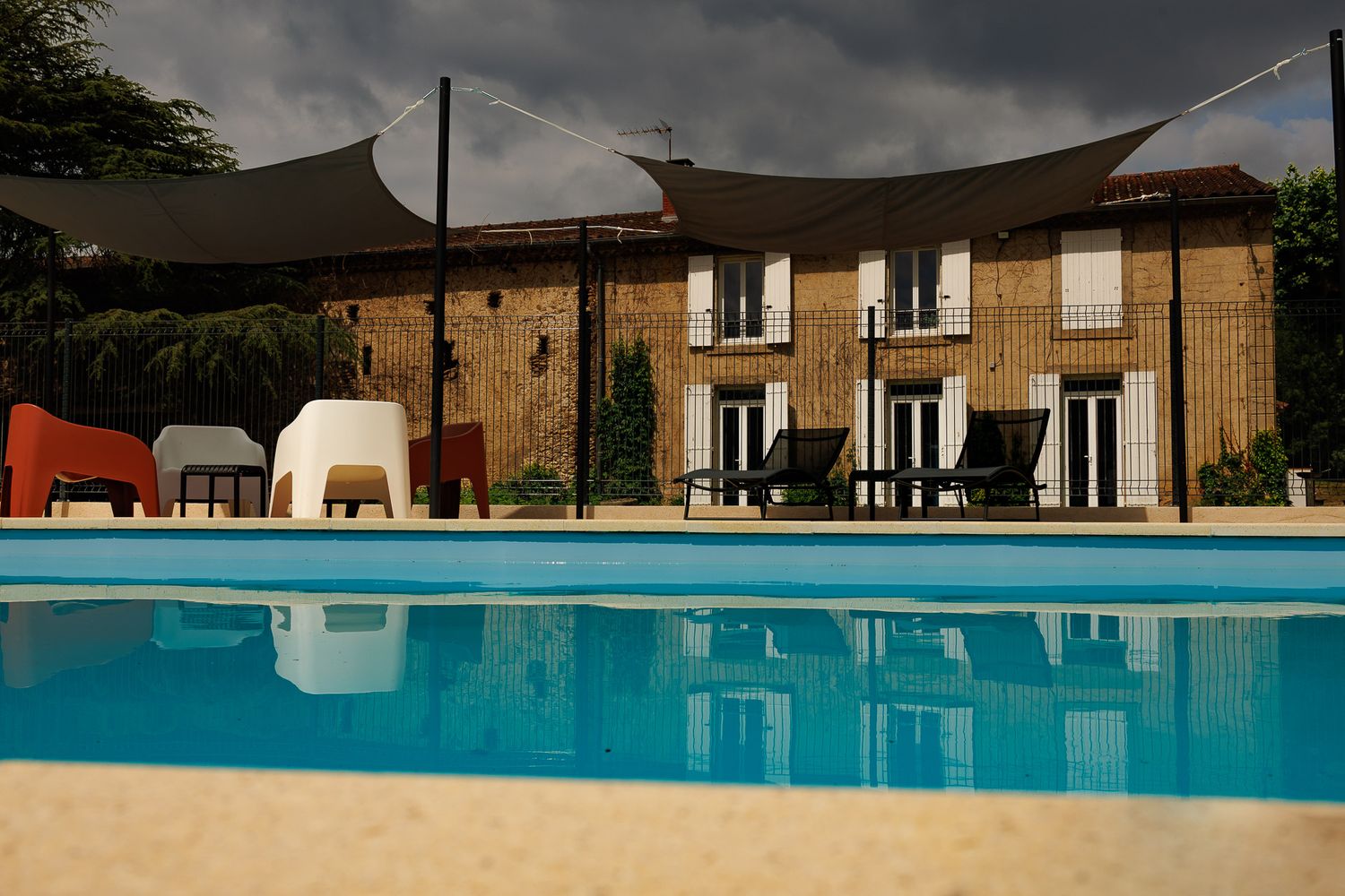 Piscine et son jardin d'extérieur devant une bâtisse  en pierre et volets blancs