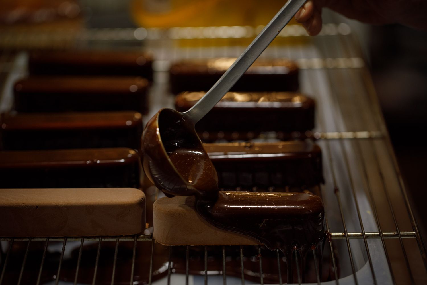 Une louche glace du chocolat sur des entremets marrons déposés sur une grille