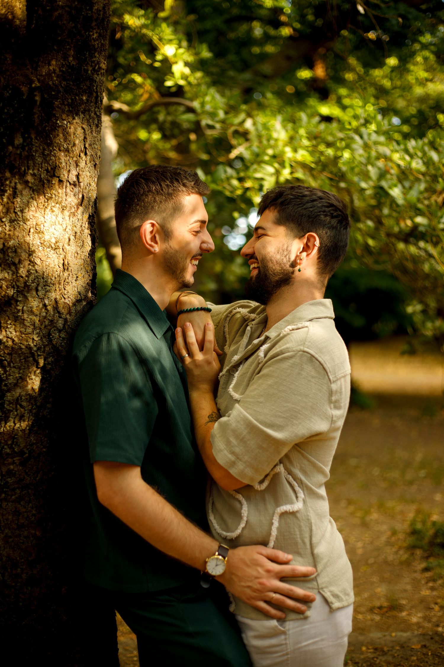 Photo d'un couple d'homme appuyé contre un arbre sourires et regards complices