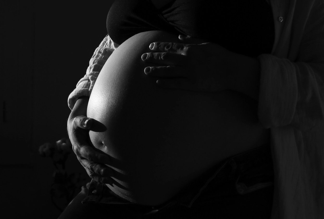 Photo noir et blanc d'un ventre rond, les mains de la future maman posées sur le ventre