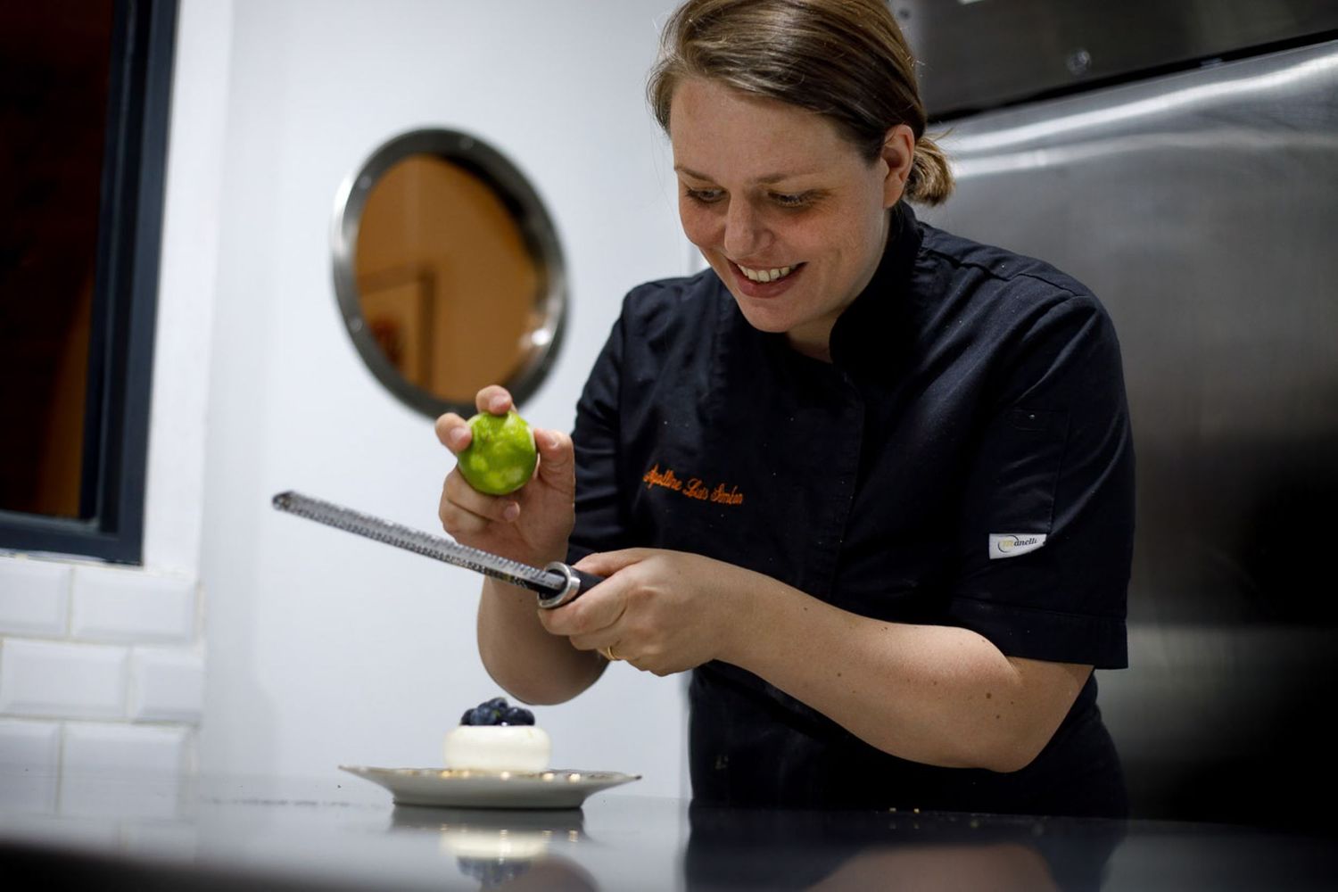 Une pâtissière décore de zeste de citron vert son entremet aux myrtilles lors d'un reportage d'artisanat à Montpellier