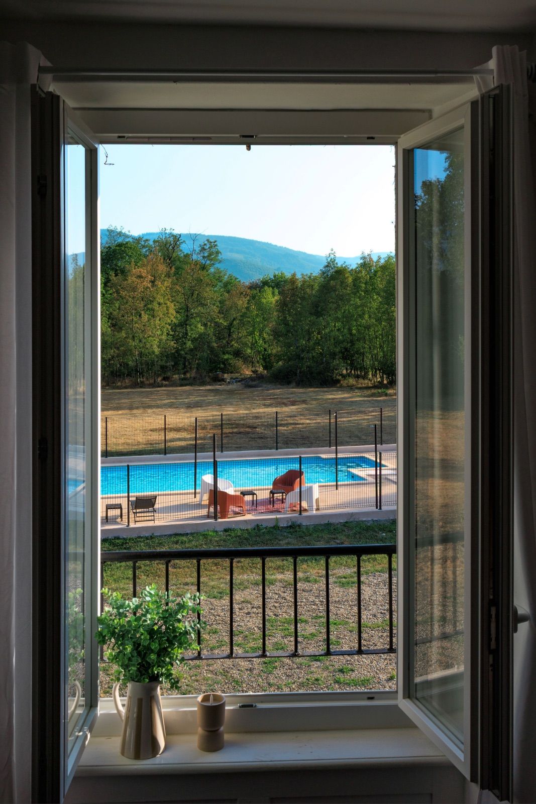 Vue depuis l'intérieur d'une chambre à travers une fenêtre ouverte sur une piscine sécurisée et vue sur la Montagne Noire