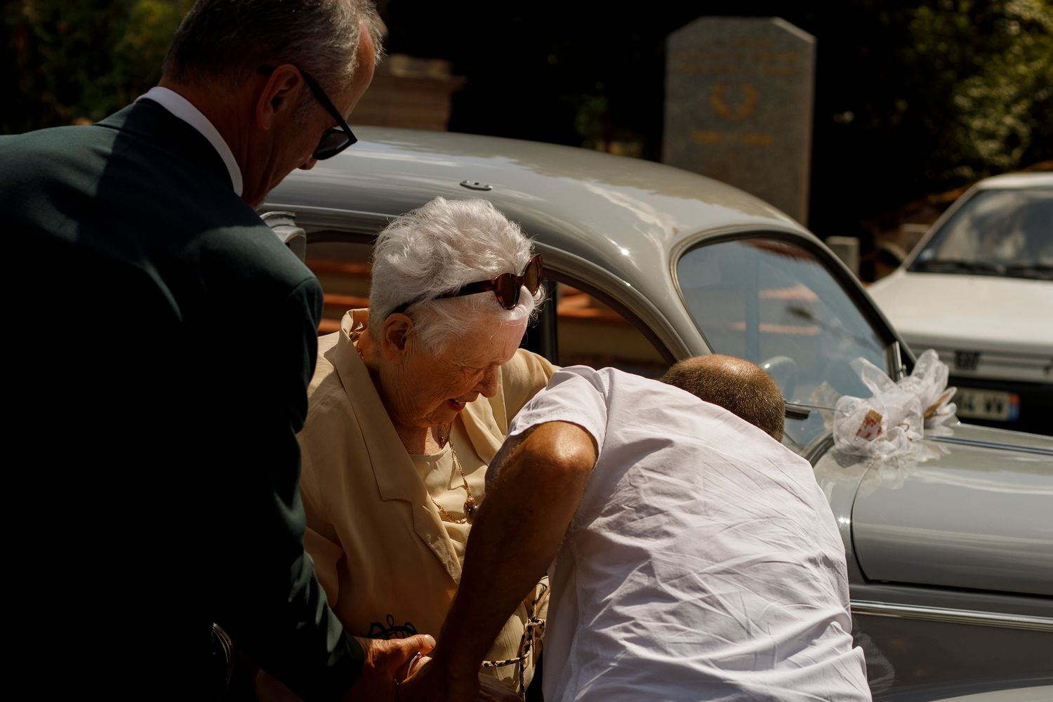 Reportage photo de mariage, tout le monde se plie en quatre pour aider la grand-mère de la mariée à sortir de la voiture de collection