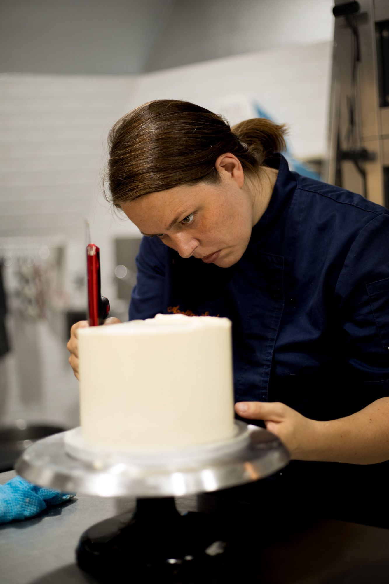 Apolline Luis Siméon, cheffe pâtissière, qui lisse un gâteau de monté de mariage.