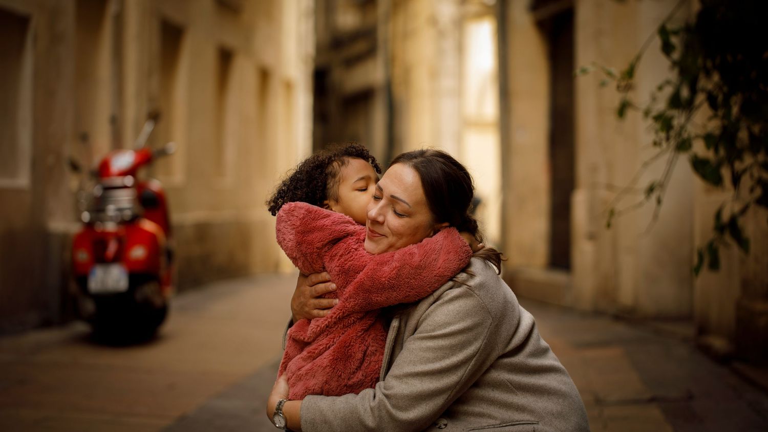 Photo d'une petite fille qui fait un gros bisou à sa maman lors d'une séance photo famille en centre-ville de Montpellier