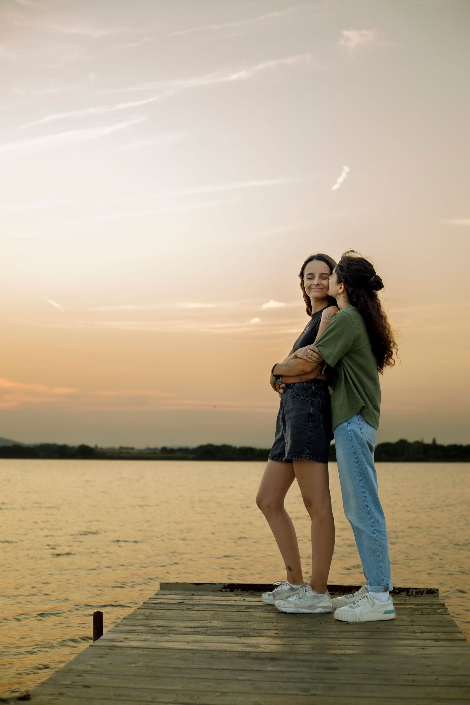 Photo d'un couple de femme qui s'enlacent sur un ponton au dessus de l'eau