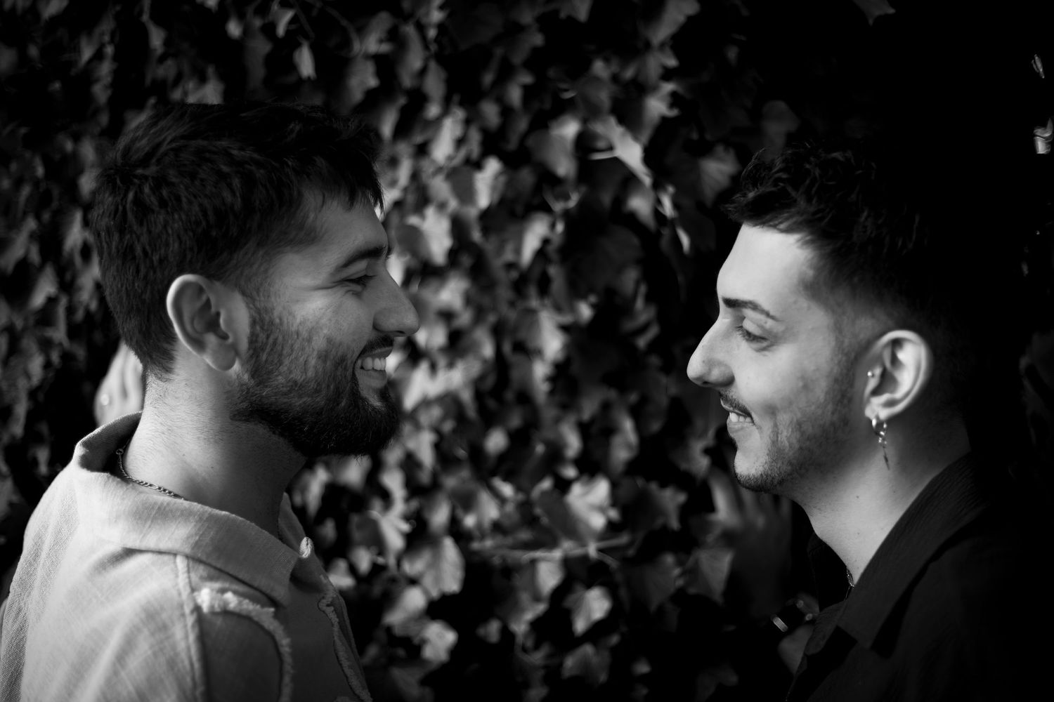 Séance photo de couple, photographie noir et blanc : deux hommes se regardent amoureusement sourire aux lèvres