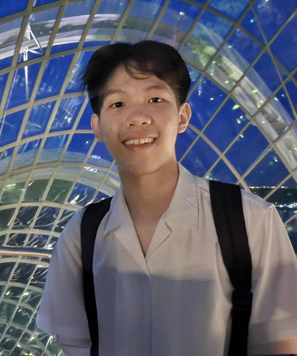 A person in a white collared shirt smiles while standing in a glass-domed architectural space.