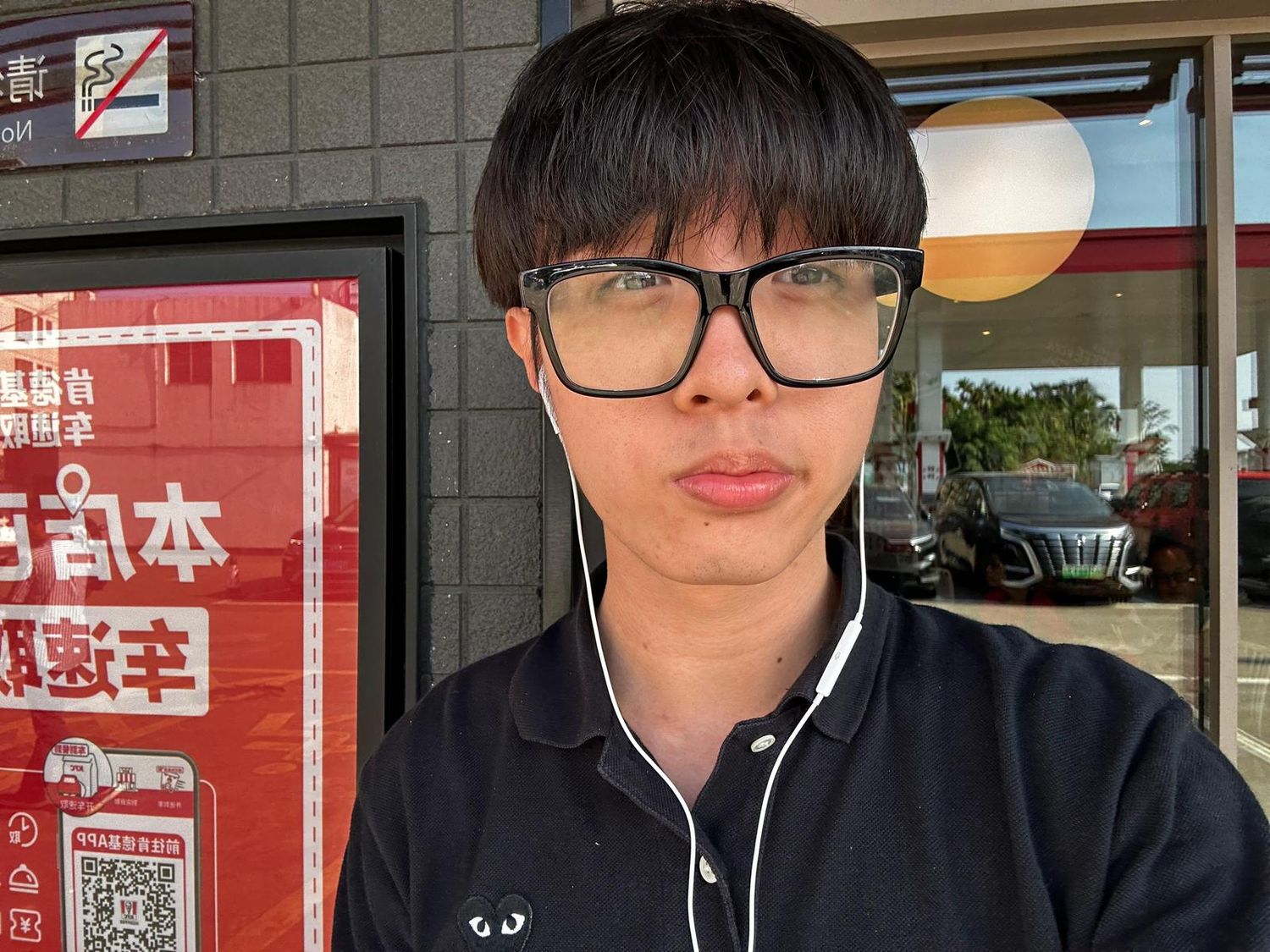 Person in glasses standing in front of Japanese signage and storefront displays at an Asian shopping center.