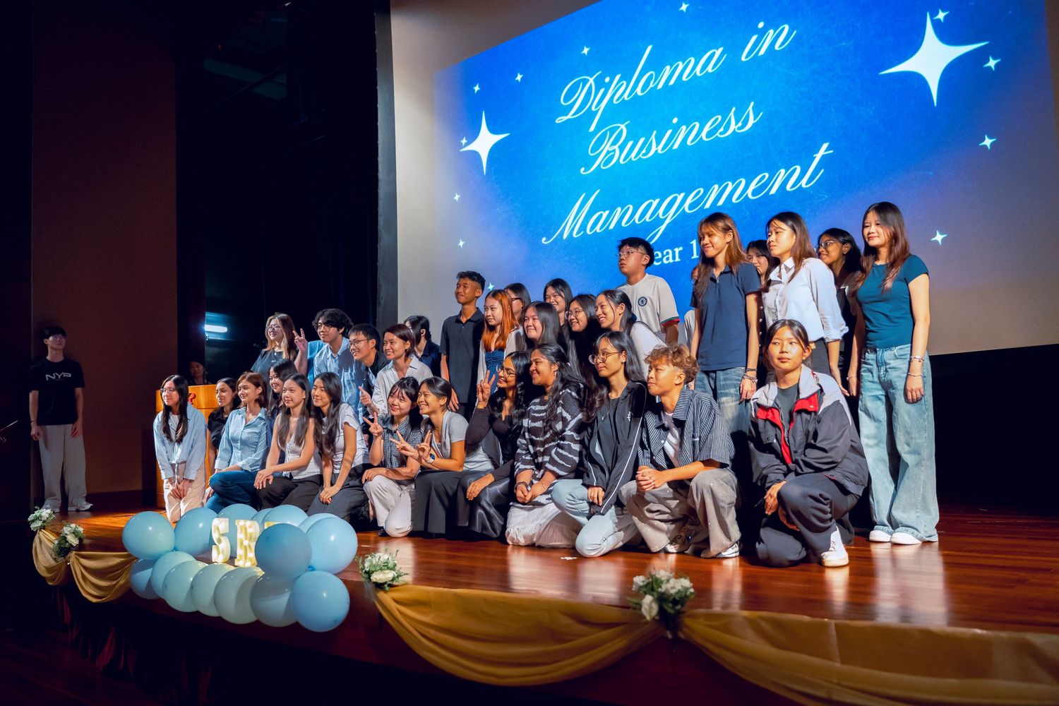 Stage performance with blue starry backdrop featuring performers in coordinated outfits.