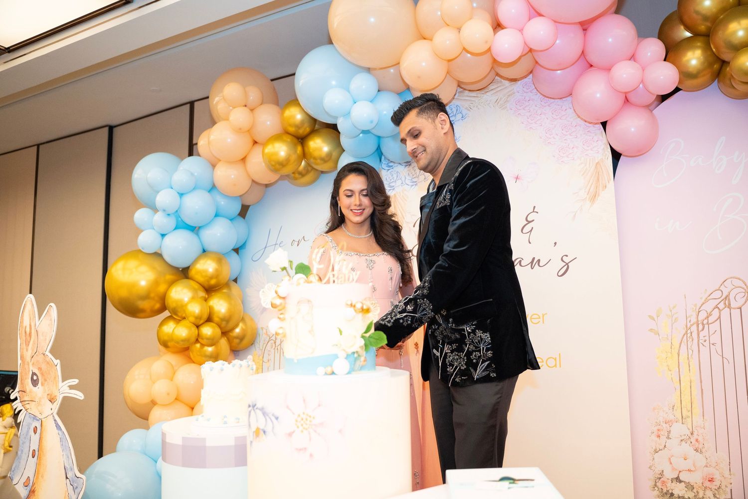 Elegant party space decorated with pink, gold and blue balloon garlands against white walls.