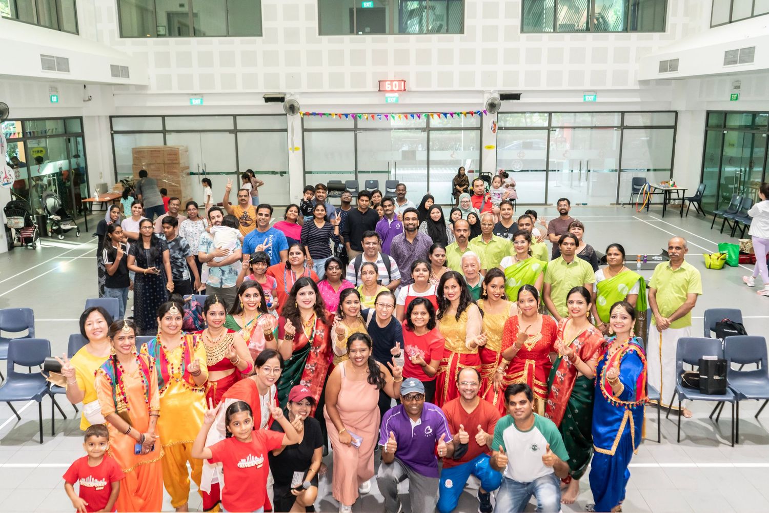 Colorful group photo of event participants wearing vibrant team shirts.