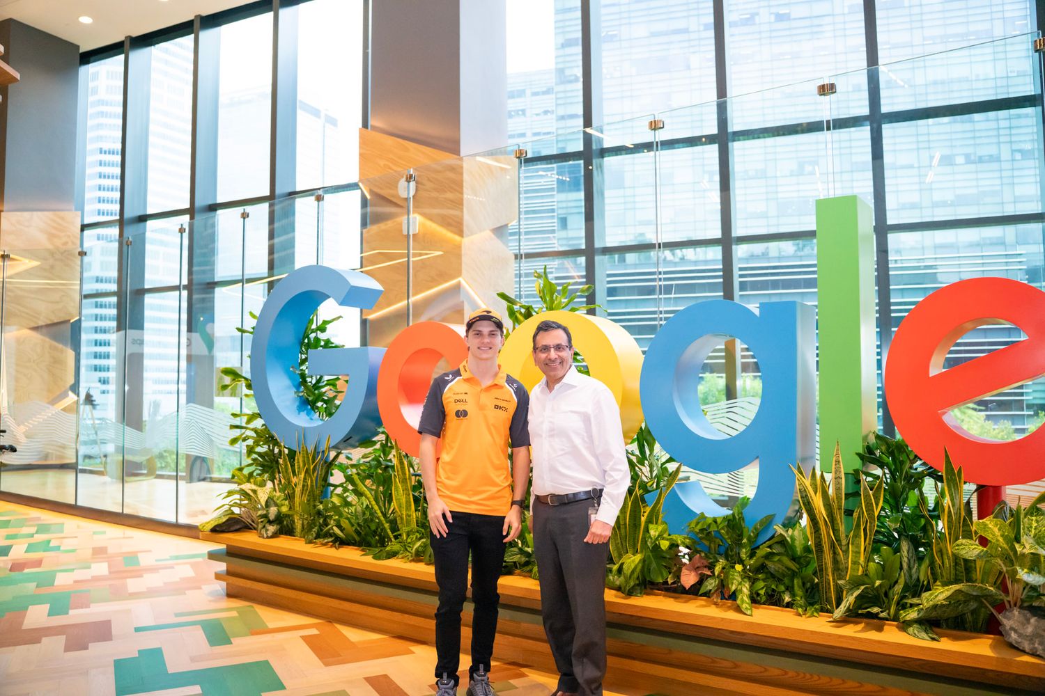 Modern office space with large windows and colorful Google logo displayed on wall.