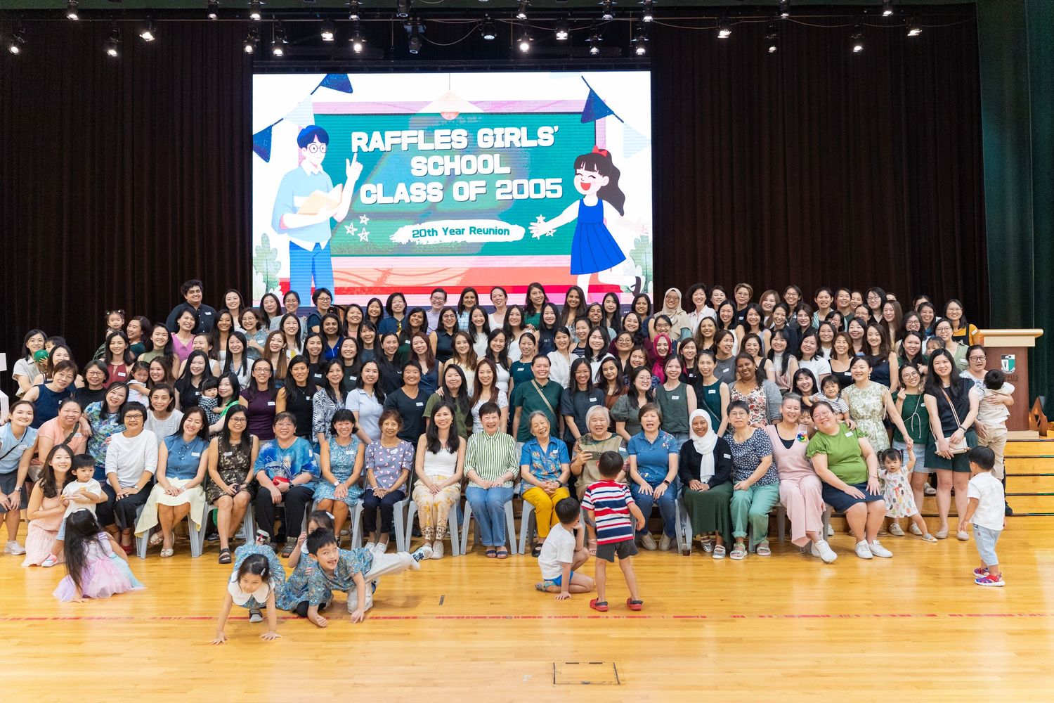 Wide angle shot of audience members seated in a gymnasium during a large indoor event.