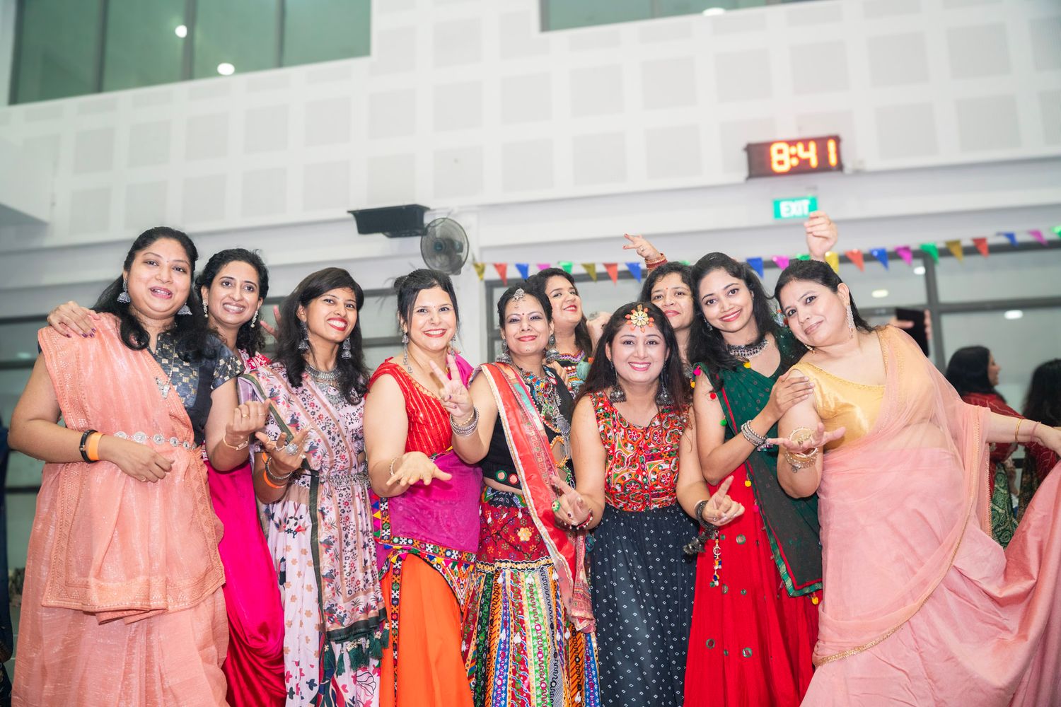 Group photo of people wearing colorful traditional Indian outfits at a celebration.