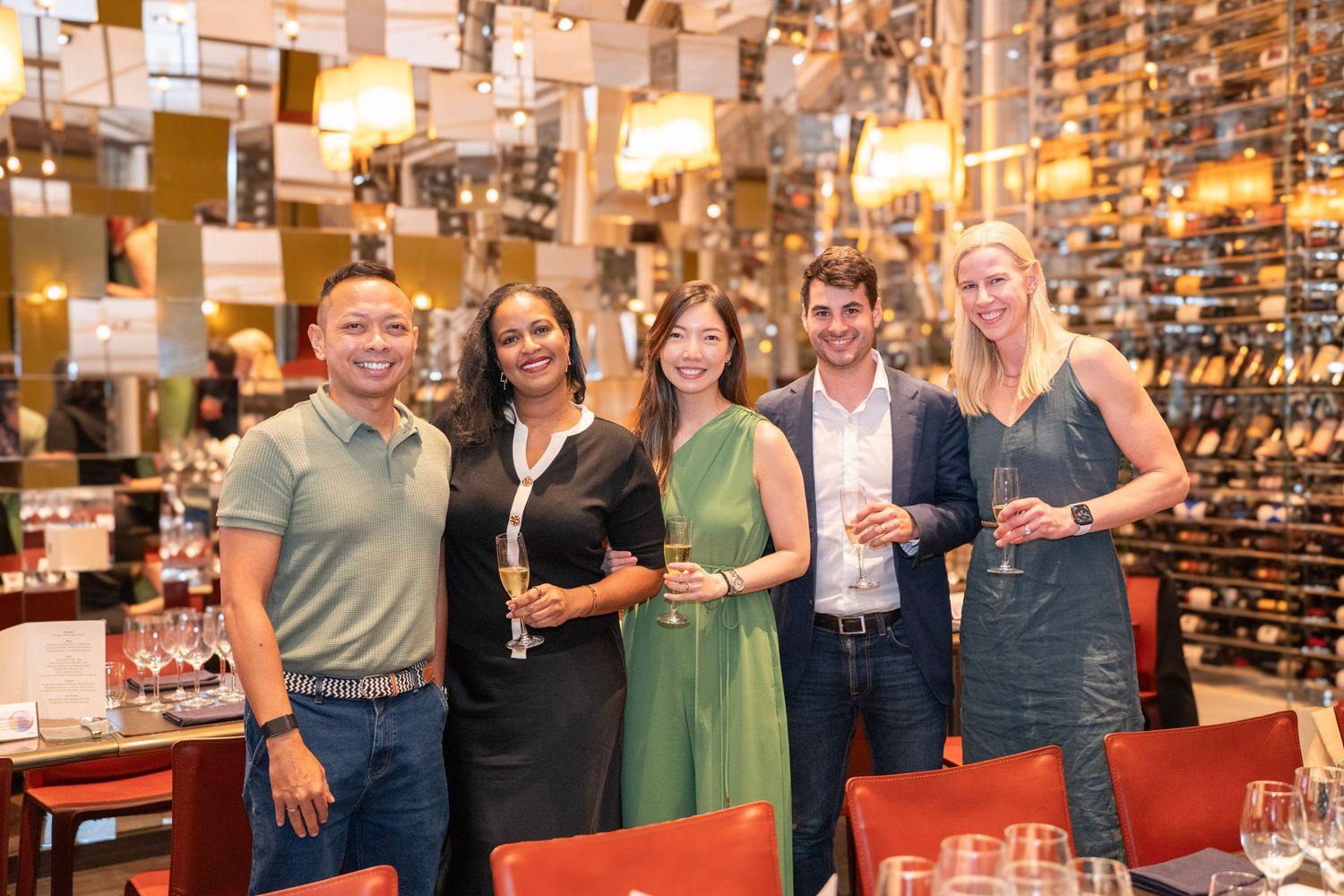 Group gathering at an upscale wine bar with elegant lighting and wine storage display.