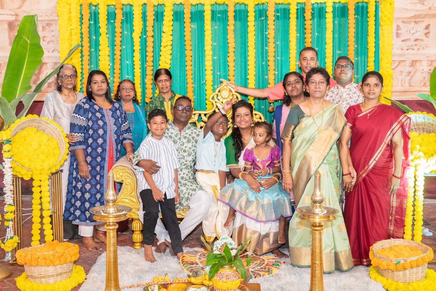 Decorated outdoor venue with yellow and turquoise drapes and floral arrangements for a special event.