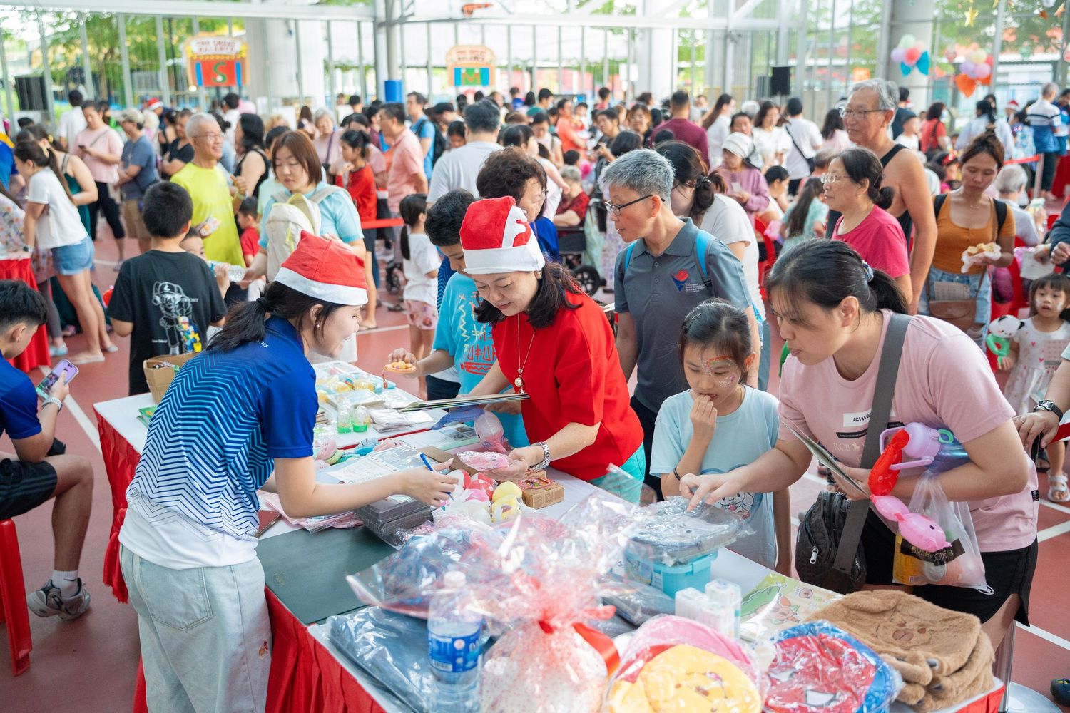 Busy community event with people gathered around tables collecting supplies and materials.