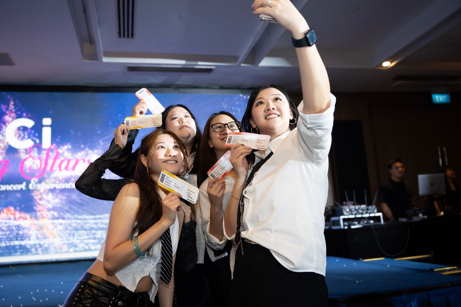 People dancing and celebrating in a dimly lit room with projection screens.