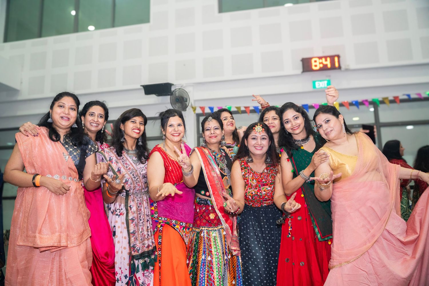 Group celebration with people wearing bright traditional Indian and Asian formal attire.