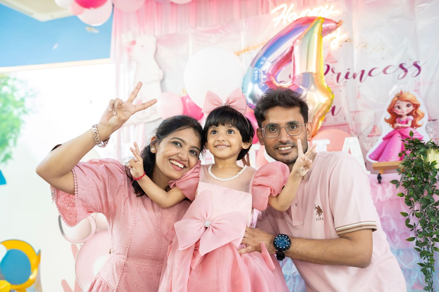 Pink themed party decorations with princess motif and festive balloon arrangements.