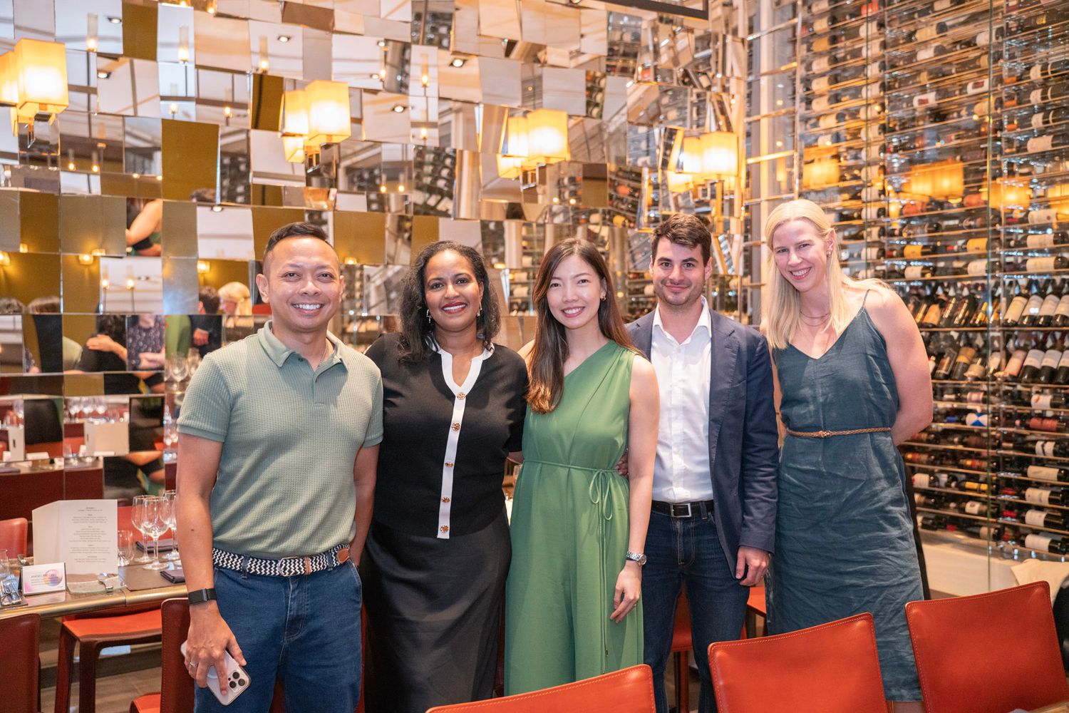 Group gathered at a restaurant or bar with warm lighting and wine glasses.