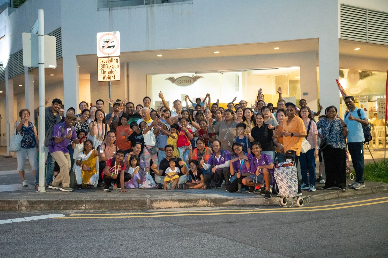 Large community gathering seated outside a modern building during a cultural event.
