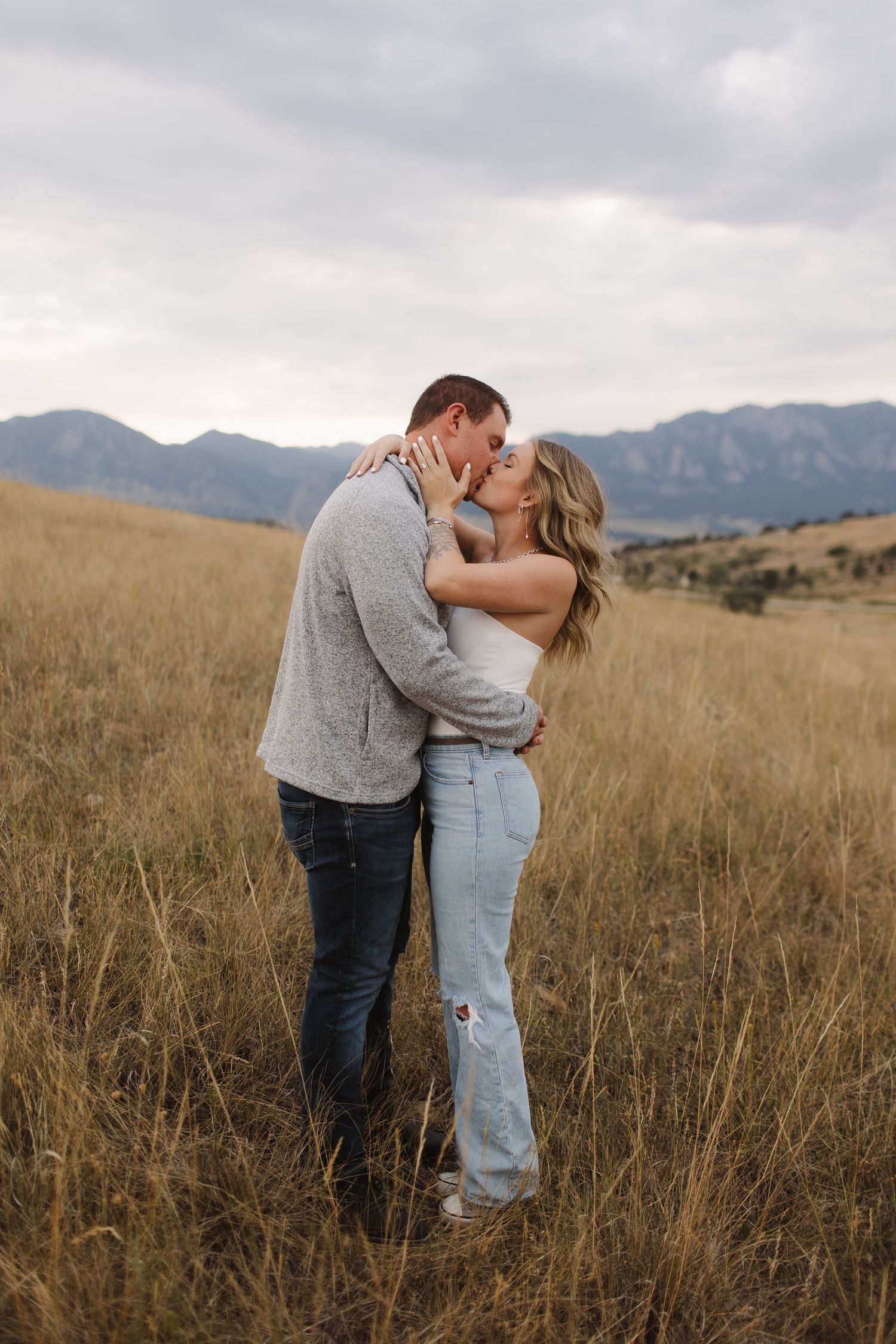 Romantic couple embracing in golden mountain meadow during sunset.