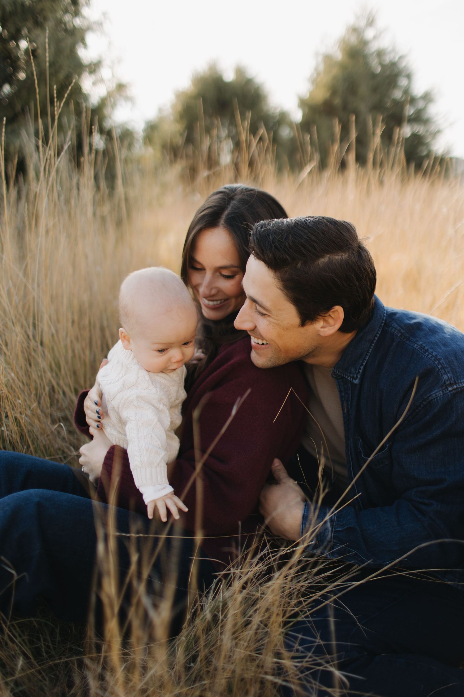 Family sharing loving moments together in a field of tall grass during autumn.