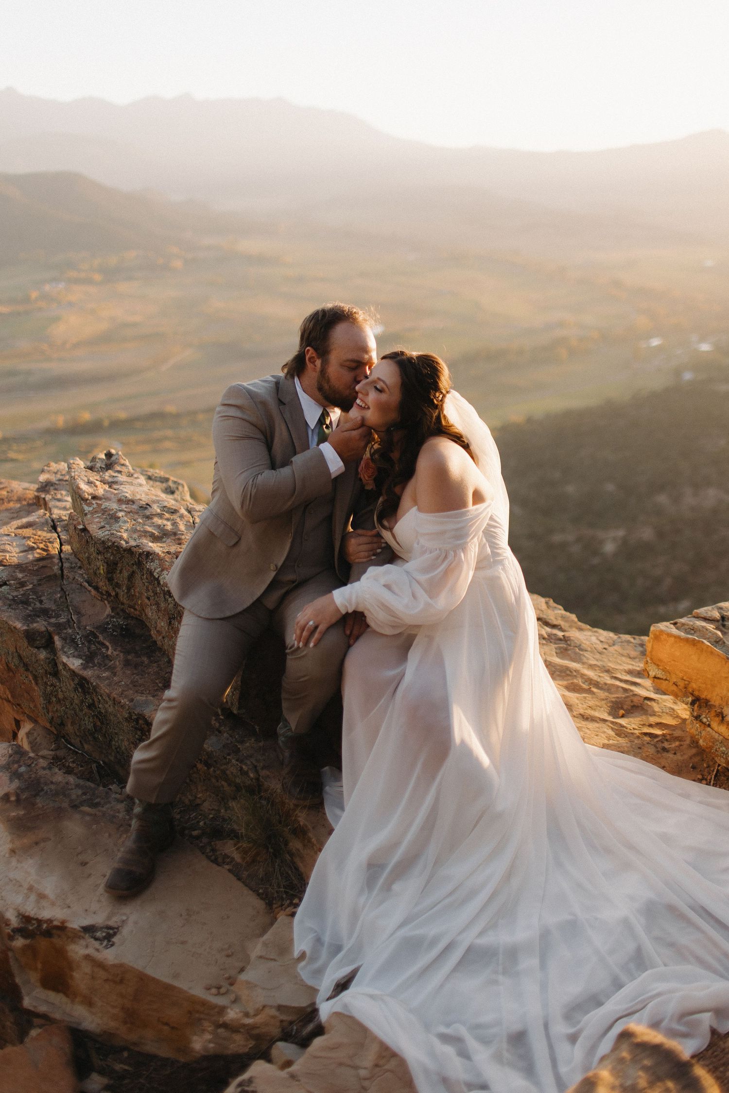 Romantic sunset portraits of newlyweds on rocky mountain overlook.
