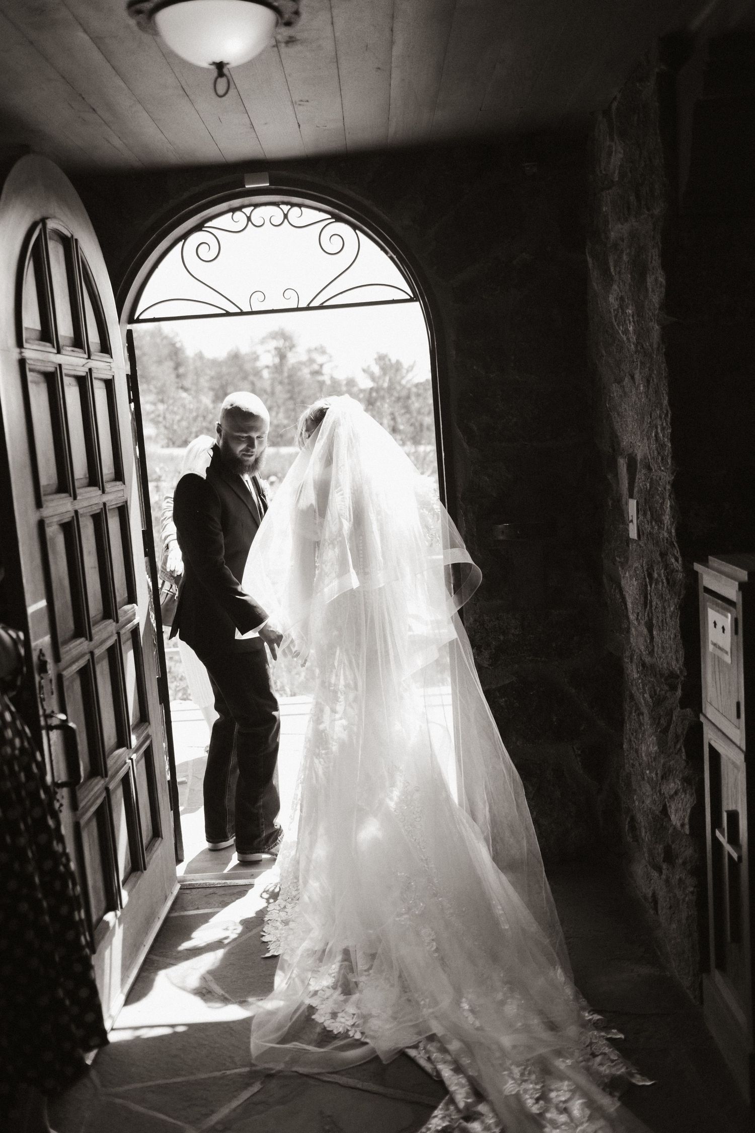 Dramatic black and white silhouettes showing a flowing wedding dress against bright doorway light.