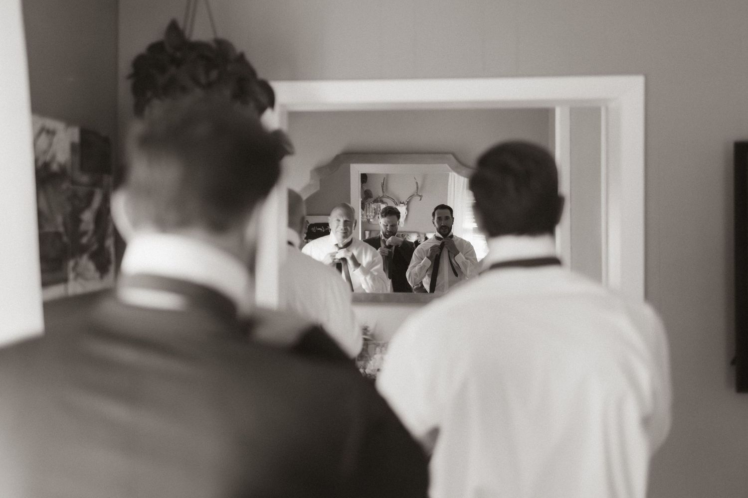 A reflection in a mirror shows wedding preparations in black and white photography.