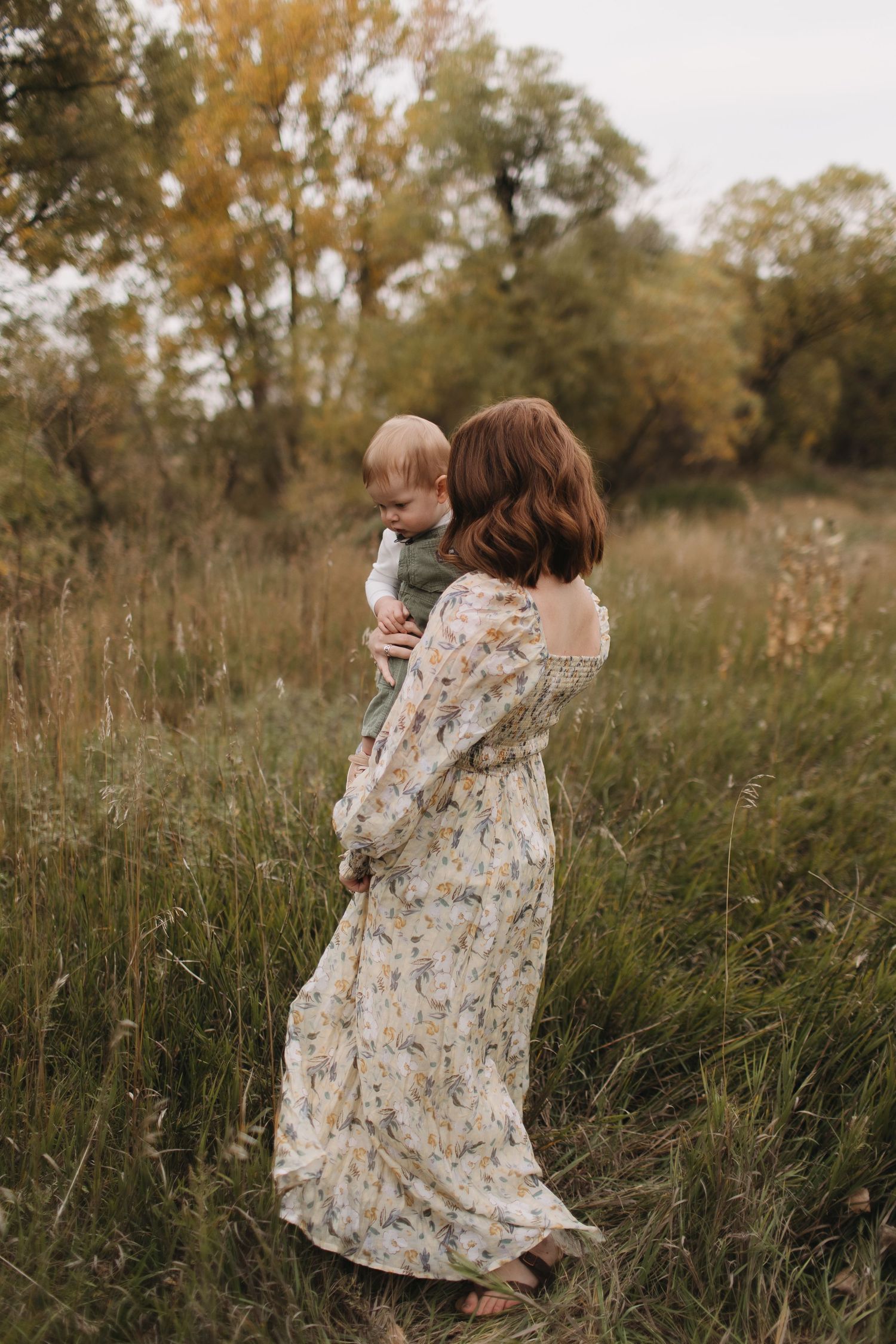 People enjoying playful moments in a field with tall grass during autumn.