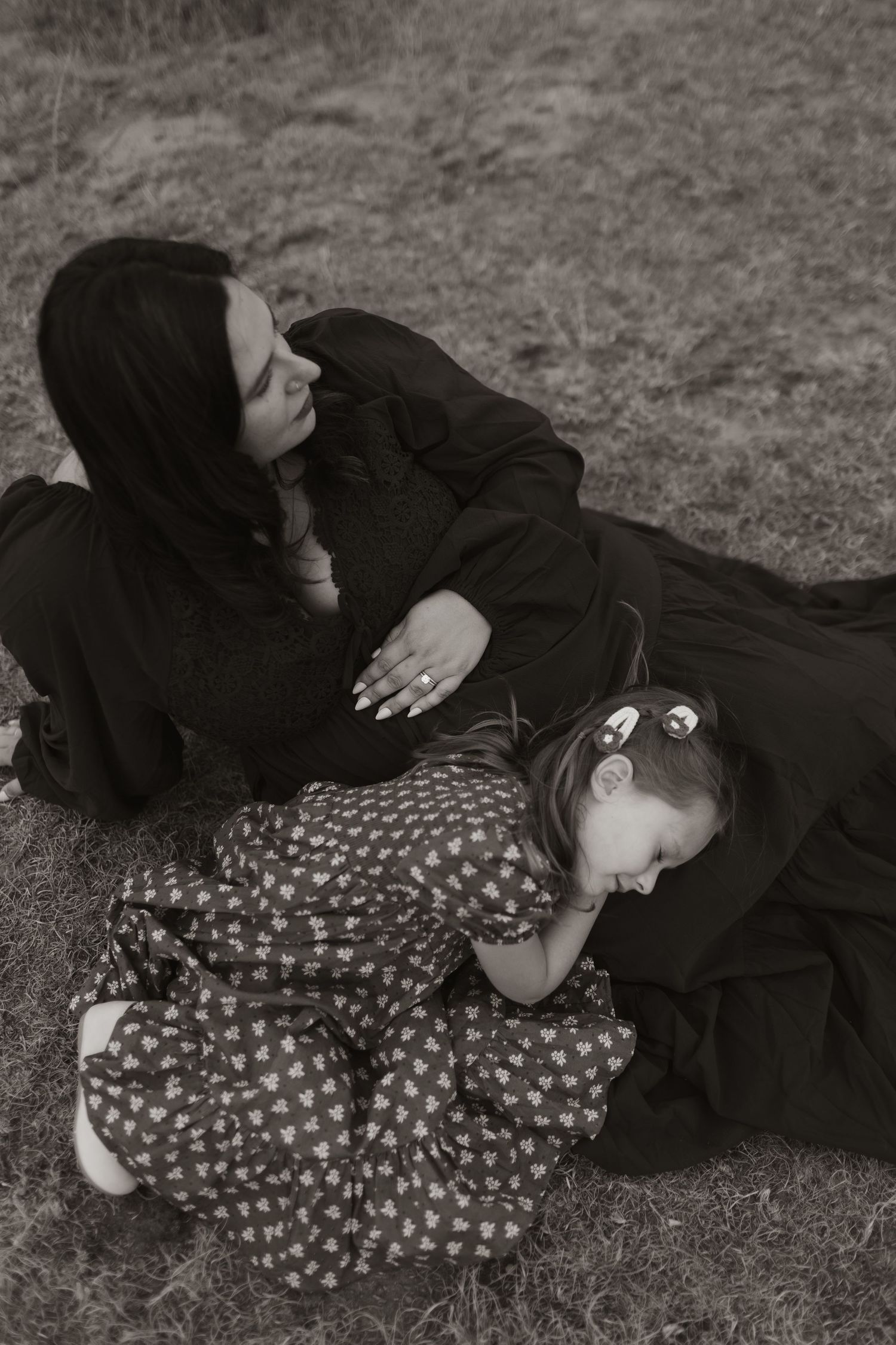 Black and white photo of two people lying together on the ground in artistic poses.