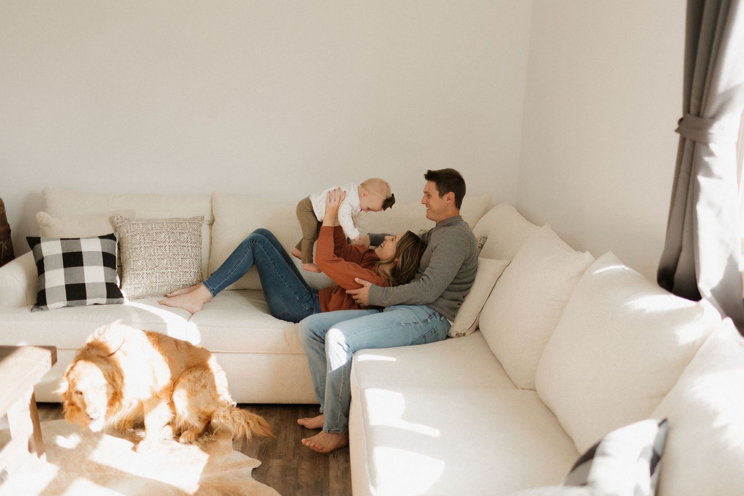 A relaxed family moment on a white sectional couch with a dog lounging nearby.